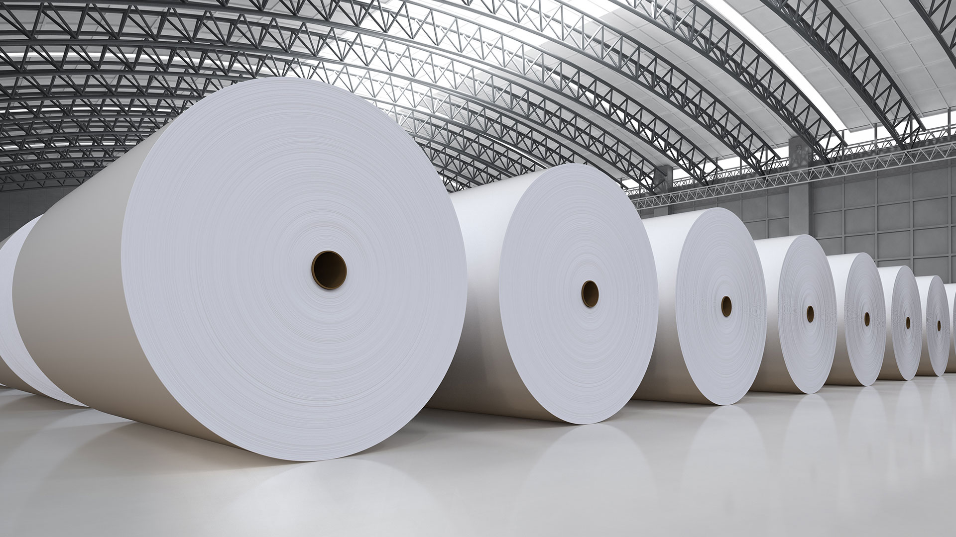 Large industrial rolls of white paper inside a warehouse.